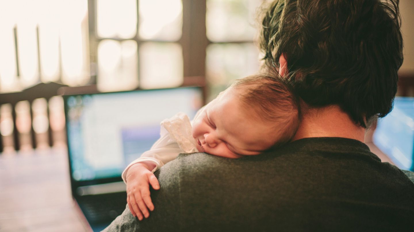 Un père et son nouveau-né dans les bras.