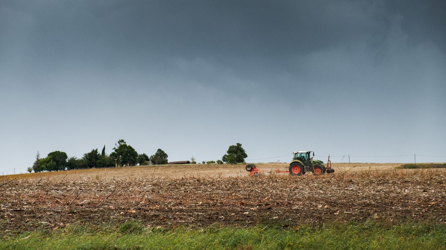 Un tracteur dans un champ, menacé par l'orage.