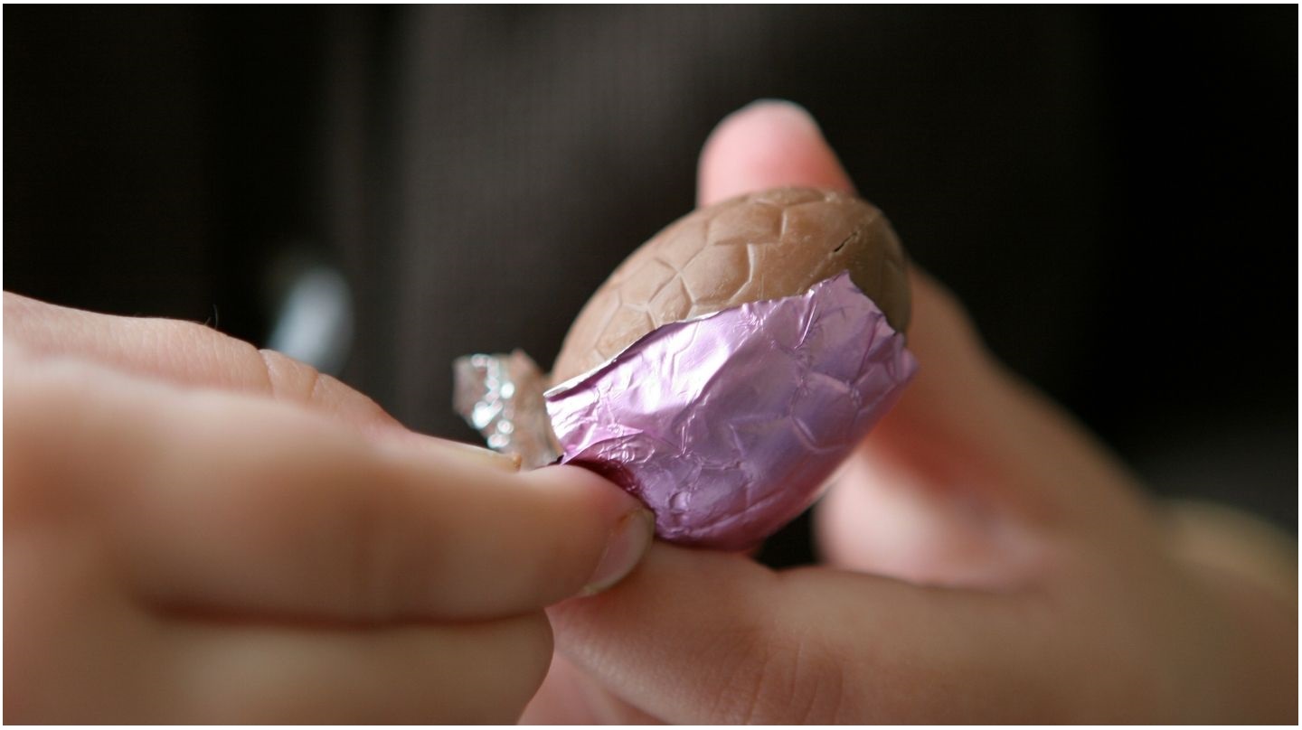 Un enfant ouvre un œuf en chocolat.
