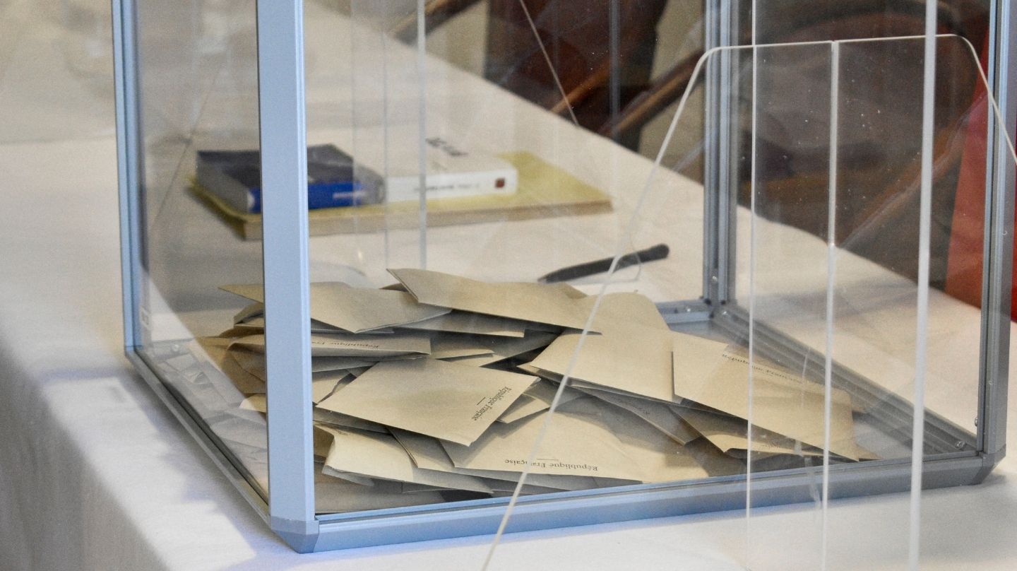 Des bulletins de vote dans une urne.