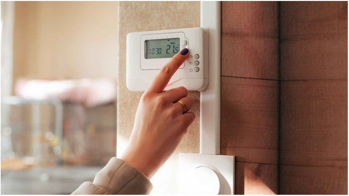 Main d'une femme réglant un thermostat