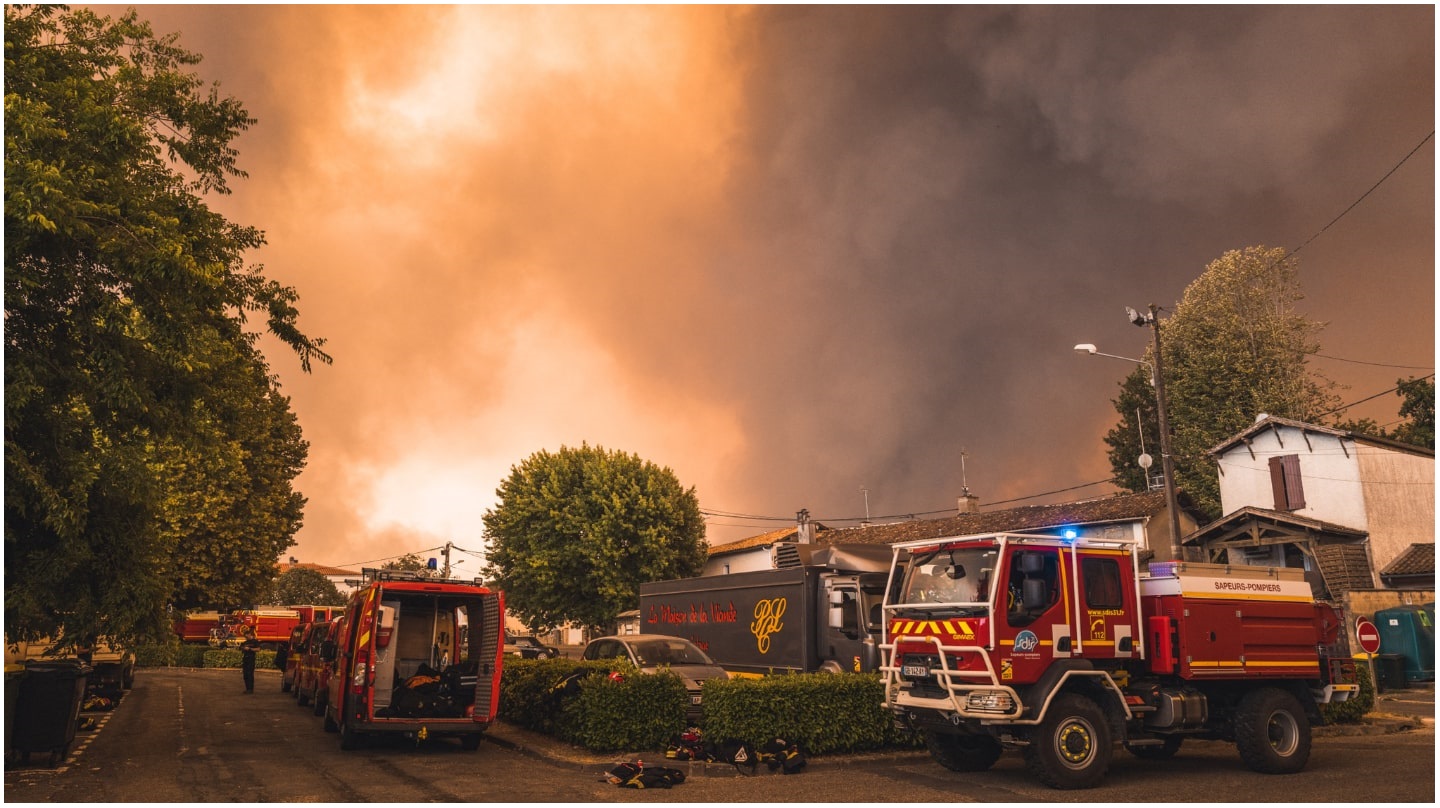 Des camions de pompiers protègent des maisons contre un incendie.