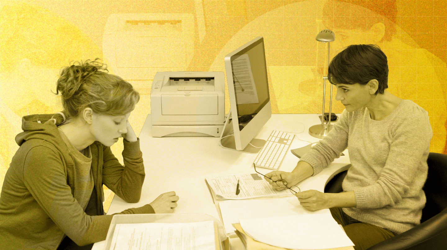 Une jeune femme, qui semble abattue, discute avec une femme à son bureau.