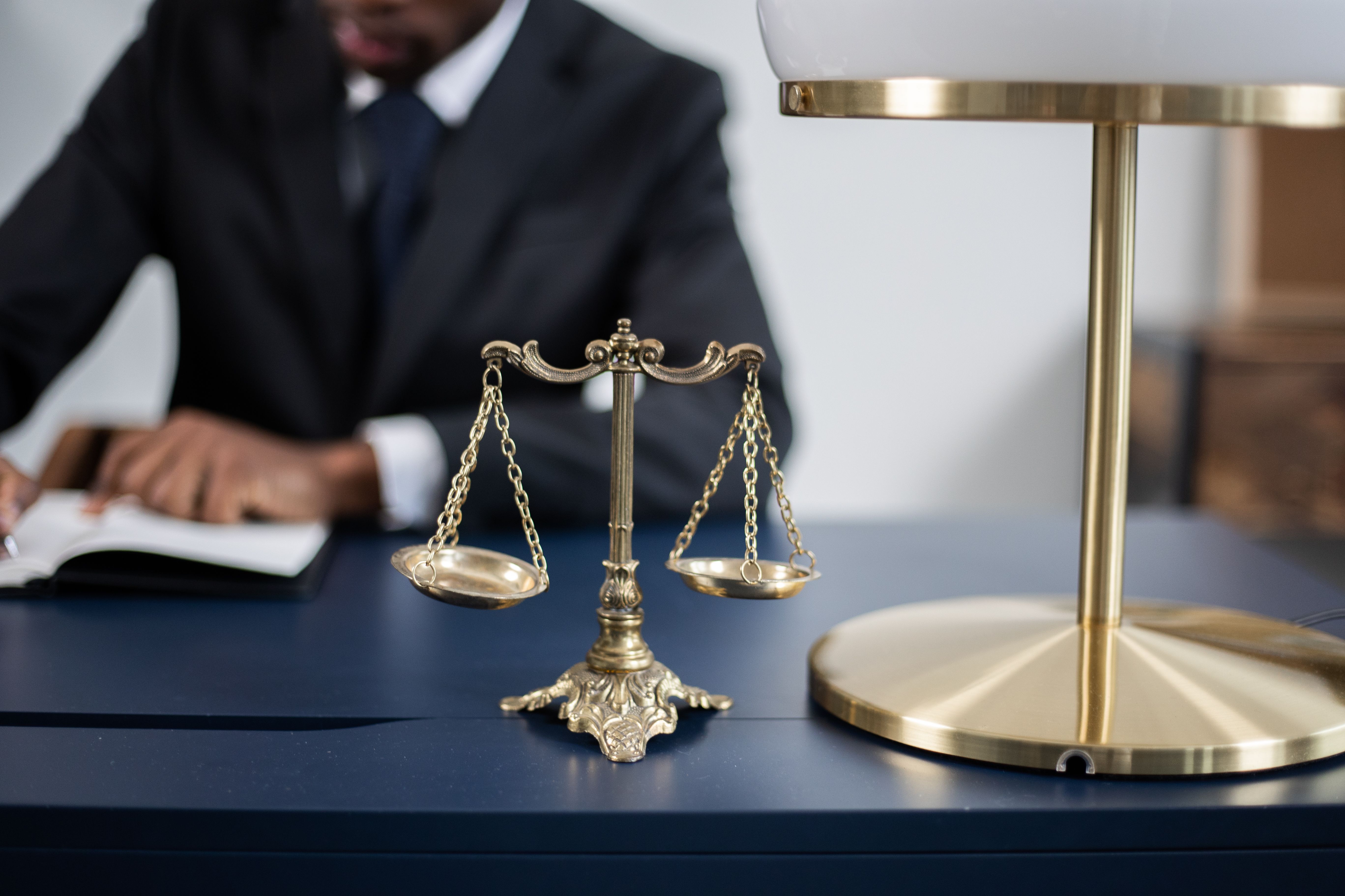 un homme écrit derrière la balance de la Justice
